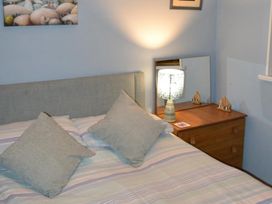 A bedroom with a bed, lamp, and mirror at Sea Side Stay 6 Pet Friendly Parking Garden Rhosneigr