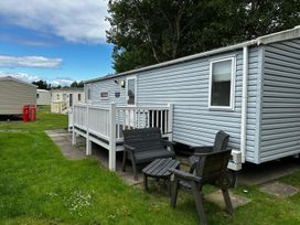 An outdoor area with a caravan and seating at a holiday park