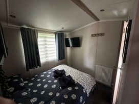 A bedroom with a bed, curtains, television, and hooks at the property