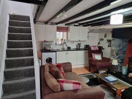 A living room with a sofa and kitchen area at a property
