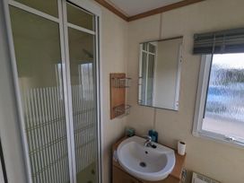 A bathroom with a shower, sink, and mirror at the property