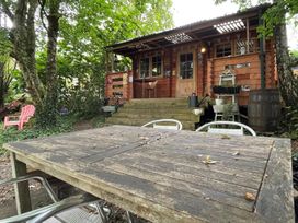 An outdoor area with a wooden table and chairs in front of a cabin with steps