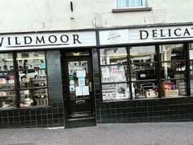 A storefront displaying food products and signage at Wildmoor Delicatessen in an urban area