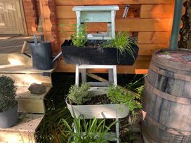 A wooden planter with various plants and a watering can at a garden