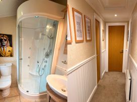 A bathroom with shower and toilet leading to a hallway at the property