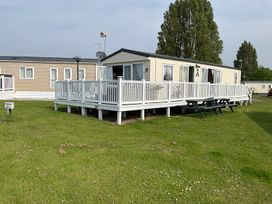 A mobile home with a deck and seating area at a holiday park