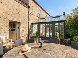 An outdoor area with a wooden table and glass conservatory at Three Mile House in Carnforth