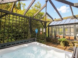 An outdoor area with a hot tub and a greenhouse at Three Mile House in Carnforth