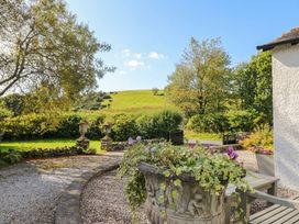 A garden with a stone planter and trees at Three Mile House in Carnforth