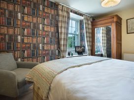 A bedroom with a bed and armchair at Three Mile House in Carnforth