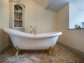 A bathroom with a bathtub and shelves at Three Mile House in Carnforth