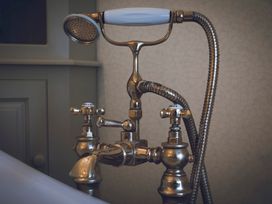 A bath tap with a shower head and controls at Three Mile House in Carnforth