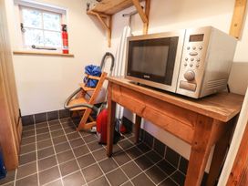 A laundry room with a microwave and vacuum cleaner at Llys Gwaun in Fishguard