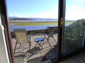 An outdoor seating area with chairs and a table overlooking the water at Aldena South Snowdon Wharf Porthmadog
