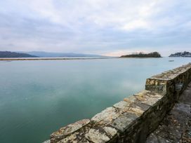 A view of water and a stone wall with an island in the distance at Aldena South Snowdon Wharf Porthmadog