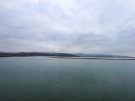 A body of water and land under cloudy skies near Aldena South Snowdon Wharf in Porthmadog