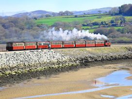 A train with carriages passing by rocks at Aldena South Snowdon Wharf in Porthmadog