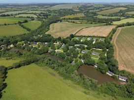 An aerial view of fields and a river with buildings along the edge at 5 Tree Tops in Dobwalls