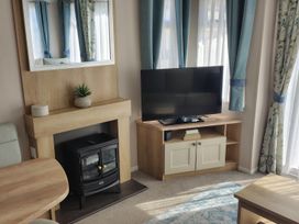 A living room with a television and a fireplace at Beverley Bay in Paignton