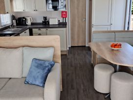 A living room with a sofa and kitchen area at Beverley Bay in Paignton