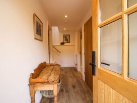 A hallway with a wooden bench and wall art at Little Red Barn Wallop near Westbury