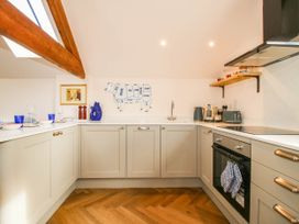 A kitchen with cabinets, sink, oven, and cow decoration at Little Red Barn in Wallop near Westbury