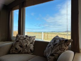 A living room with a couch and a view outside at Bwlchgwyn - Bwlchgwyn Caravan, Aberdaron Pwllheli