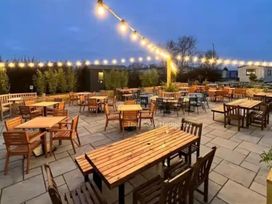 An outdoor seating area with wooden tables and chairs at The Cosy Hedgerow in Wigton