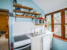 A kitchen with a stove, sink, microwave and shelves at The Old Forge in Kingsbridge