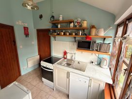 A kitchen with appliances and shelves at The Old Forge in Hallsands