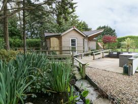 A garden with a wooden building and seating area at Brambleside Lodge in Truro