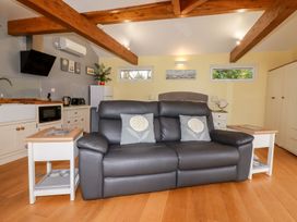 A living room with a sofa and kitchen in Brambleside Lodge Truro