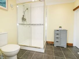 A bathroom with a shower, toilet, and cabinet at Lower Brambleside Truro