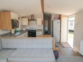 A kitchen with a sofa, refrigerator, stove and dining table at 14 Pines in Cayton Bay