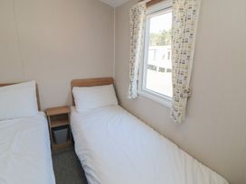 A bedroom with two beds and a window at 14 Pines in Cayton Bay