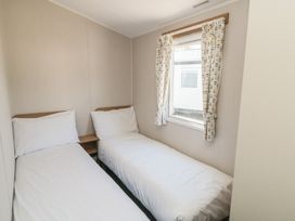 A bedroom with two single beds and a window at 14 Pines, Cayton Bay