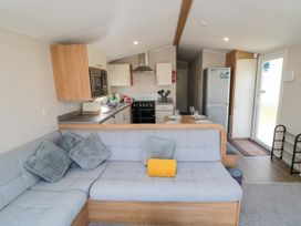 A living room with kitchen unit and sofa at 14 Pines in Cayton Bay