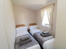 A bedroom with two single beds and a window at 14 Pines in Cayton Bay