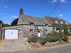 A cottage with a garage and flower beds at Farthing Cottage Corfe Castle