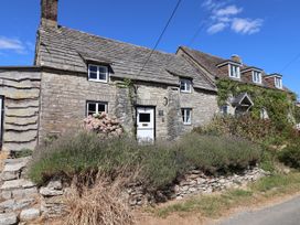 A cottage with stone walls and flowers outside at Farthing Cottage in Corfe Castle