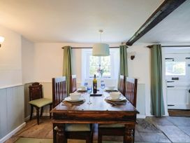 A dining room with a table set for meals at Farthing Cottage in Corfe Castle