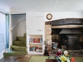 A living room with a fireplace and bookshelf at Farthing Cottage in Corfe Castle