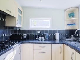 A kitchen with a sink, countertop, and appliances at Farthing Cottage in Corfe Castle
