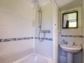 A bathroom with a shower and sink at Farthing Cottage in Corfe Castle