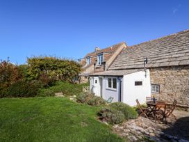 A house with a garden and seating area at Farthing Cottage Corfe Castle