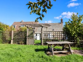 A garden with a wooden table and fence at Farthing Cottage in Corfe Castle