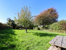 A garden with green grass and trees at Farthing Cottage in Corfe Castle