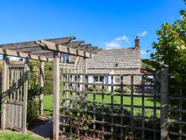 An outdoor area with a wooden pergola and gate at Farthing Cottage, Corfe Castle
