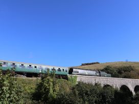 A train passing over a bridge surrounded by greenery at Farthing Cottage in Corfe Castle