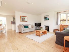 A living room with a sofa, coffee table, and television at Cloudbreak in Wadebridge